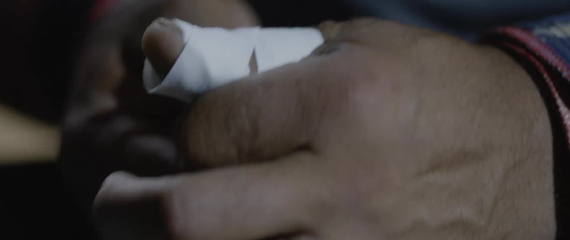 Man wraps his thumb with tape and then makes a fist