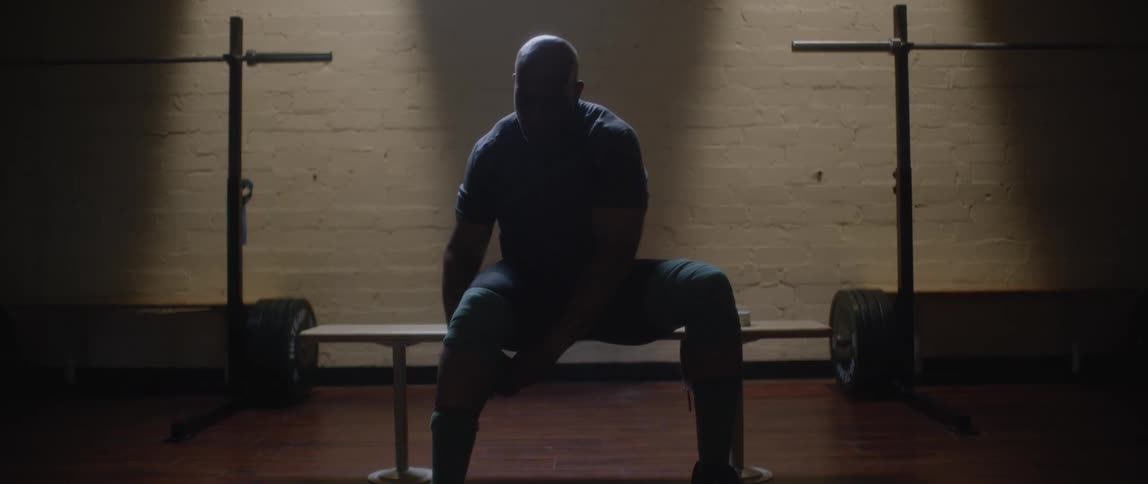 Silhouette of a seated man placing a protective bandage on his knee