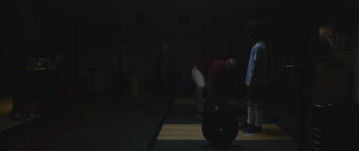 Man putting weights on a barbell for a boy