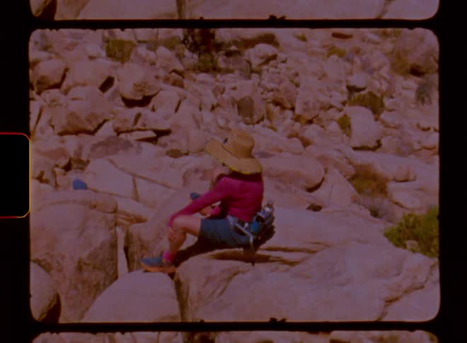 A person wearing a straw hat is sitting on a rock in an environment full of them