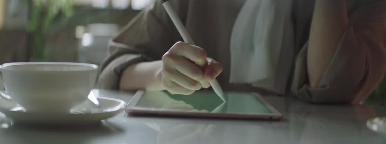 Person sitting and using a tablet with a stylus