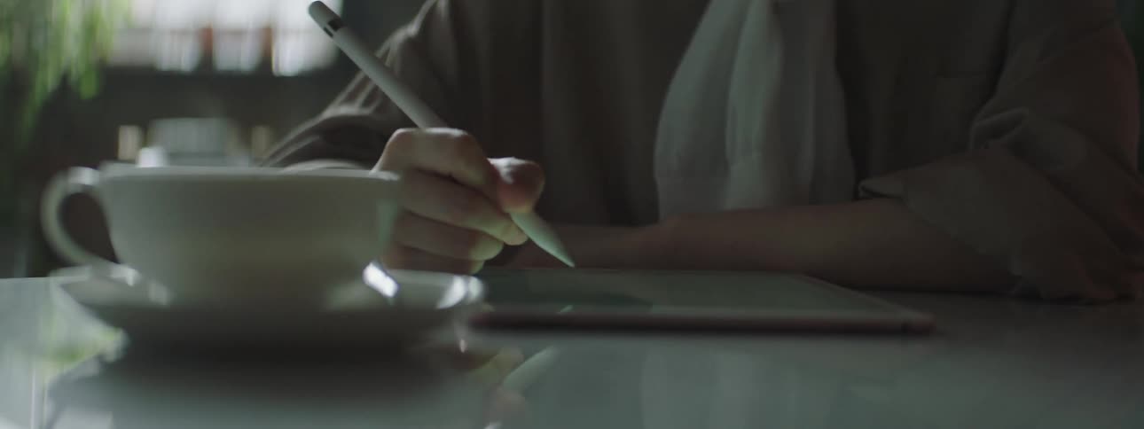 Person sitting and using a tablet with a stylus