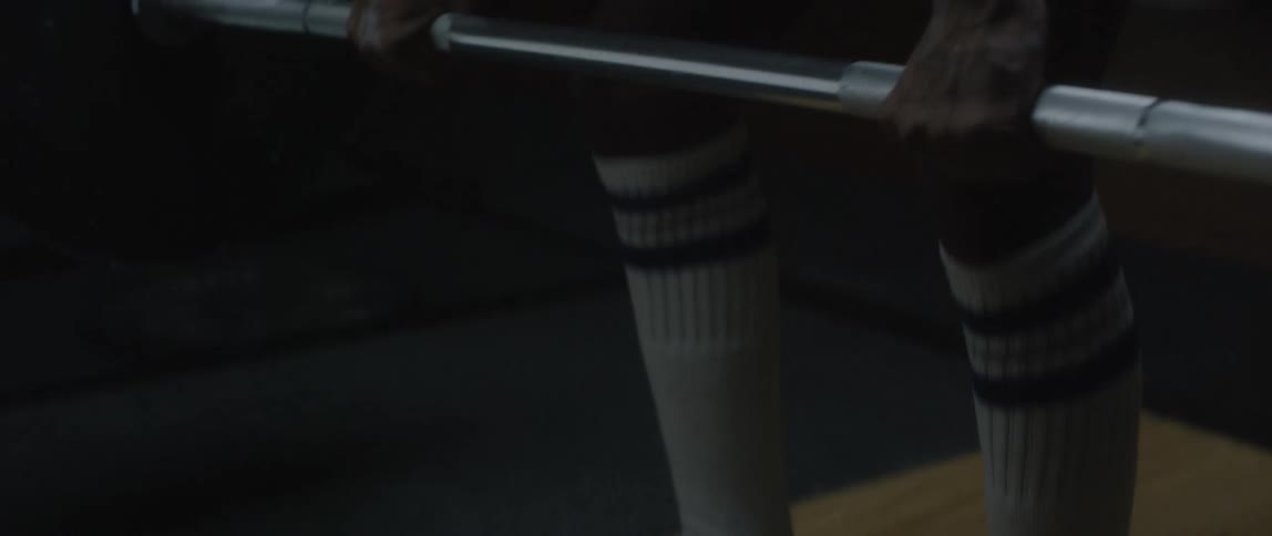 Person picking up a free weight bar and lifting it