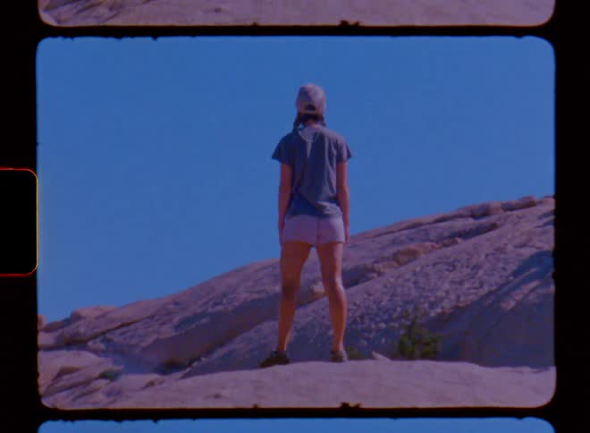 A woman is standing on a large boulder