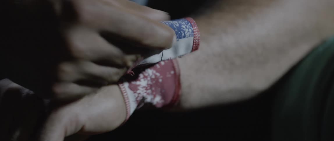 Closeup of a mans hands tying a wrist strap for weightlifting protection