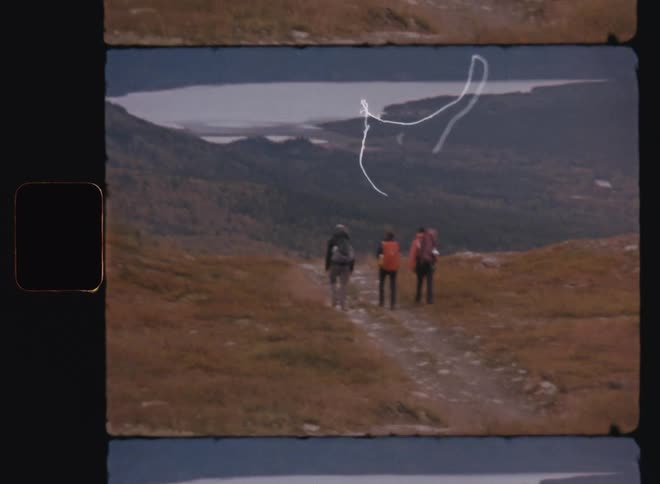 Three people walking on a natural trail beneath the mountains