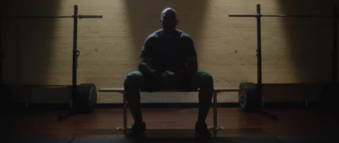 A black man sitting on a weight bench