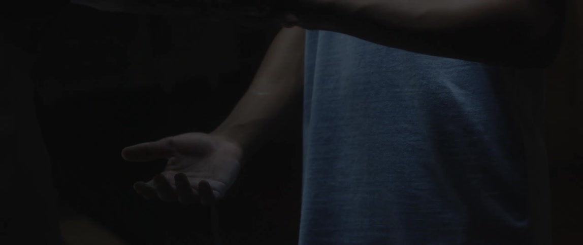 Man applies chalk dust to youths hand while standing in dimly lit area