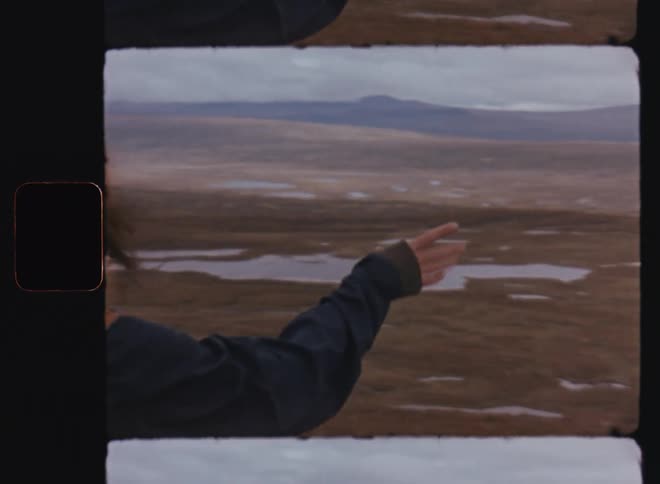 Man and woman with their backs turned observing a natural landscape with ground and mountains from above