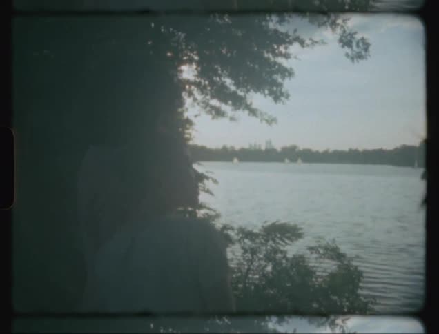 People on the edge of a lake watching boats in the water