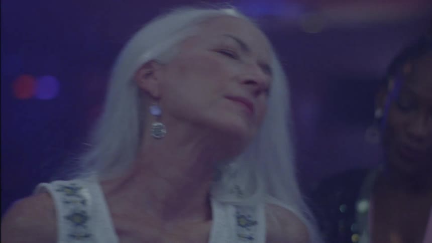 Portrait of an elderly woman dancing and having fun in a hall with music