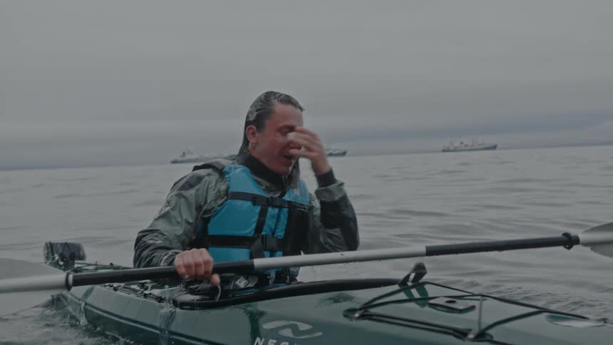 A man riding a canoe while wearing a vest in the sea