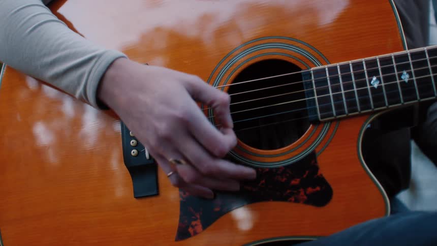 A persons hands playing the strings of a guitar