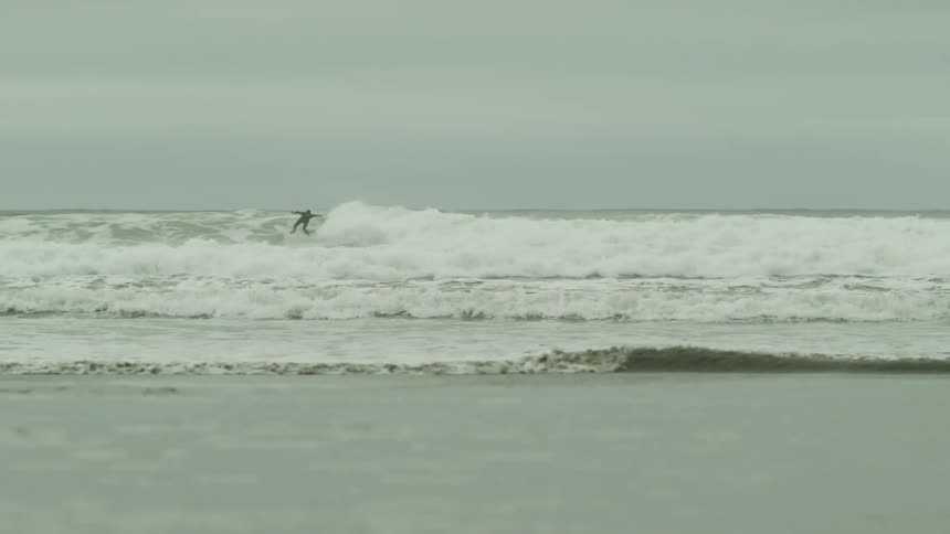 Man surfing a wave in a cloudy sky