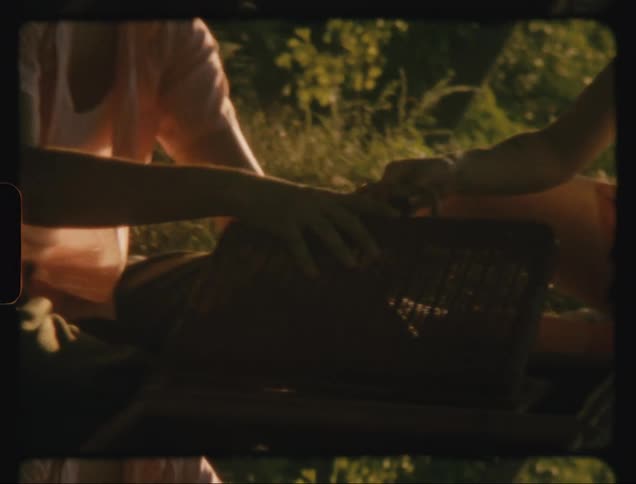 Man and woman sitting by a lake opening a small basket