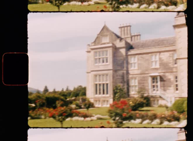 A large mansion with a flower garden during the sunny day