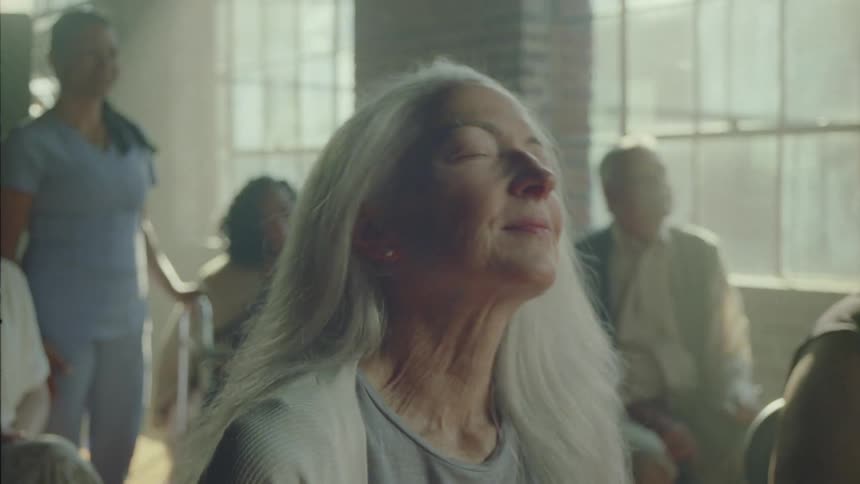 An elderly woman sits and sings and relaxes and moves her head