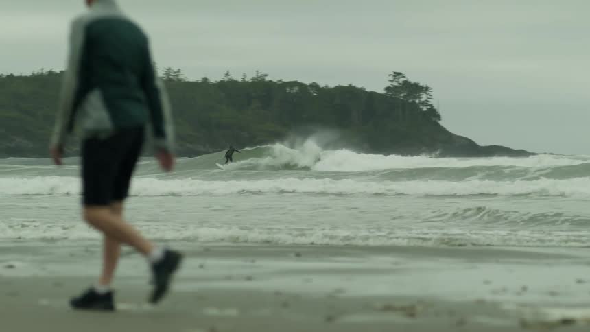 A surfer riding a wave towards the beach
