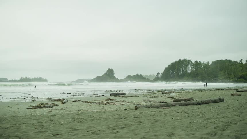 A beach with odnas breaking on the edge and there is a surfer in the water