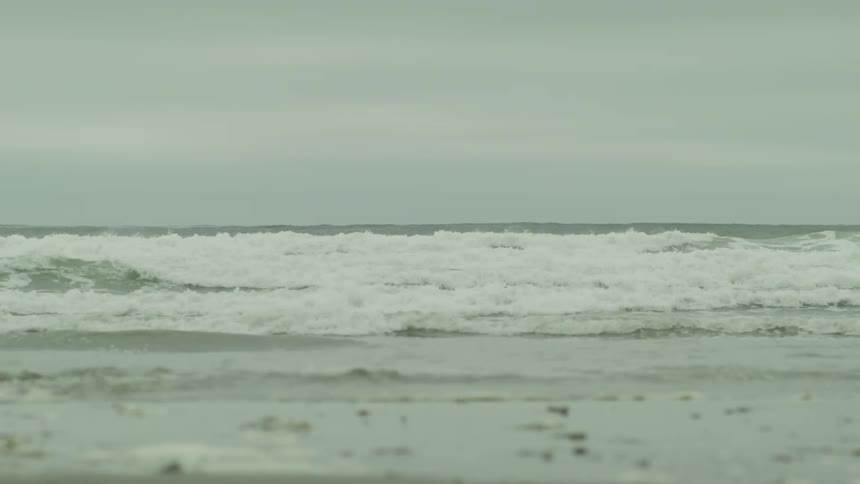 Male surfer carrying a surfboard runs by the wavy sea