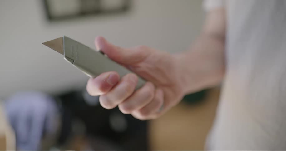 Closeup of a mans hands opening and closing a box cutter