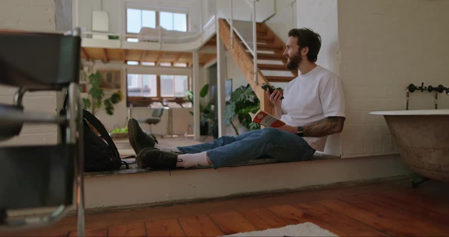 A man sitting on the floor reading a book