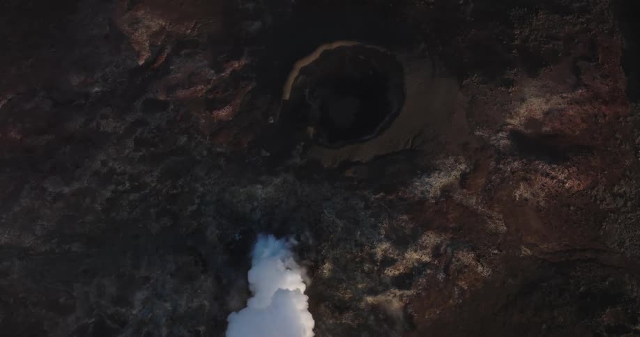 A rocky ground with a hole coming out of white smoke