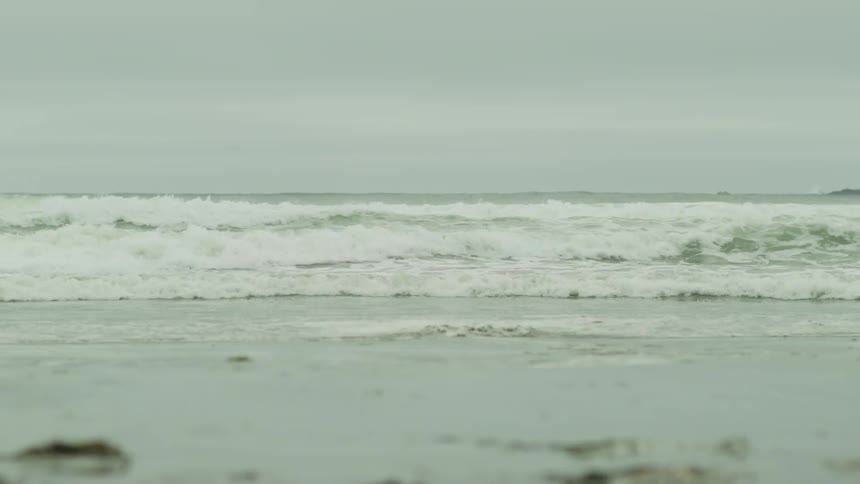 Small waves reaching the sandy shore on a cloudy day