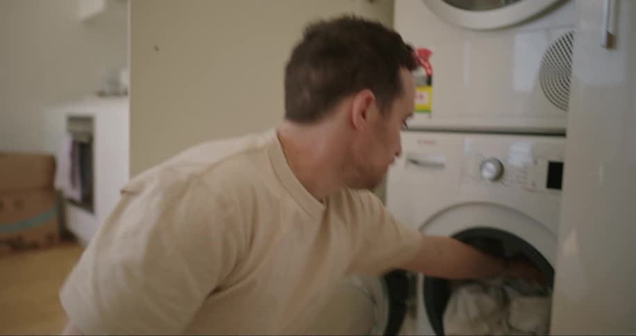 A man loads a washing machine with laundry