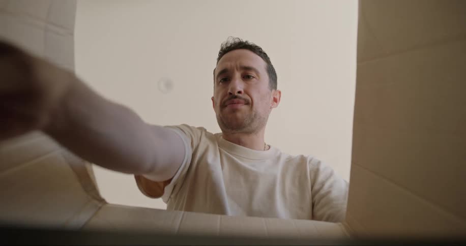 Man grabbing a cup from inside a cardboard box