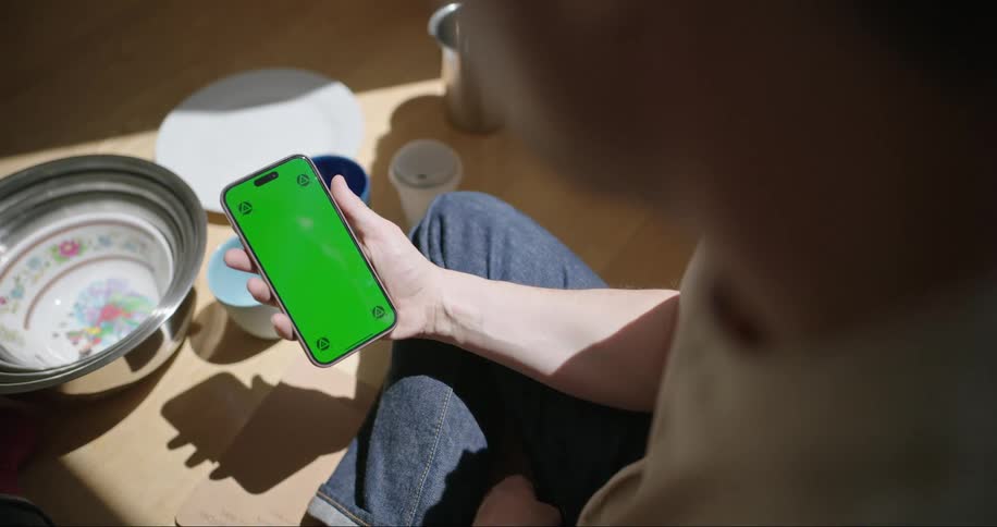 A man sitting indoor while staring at his mobile device