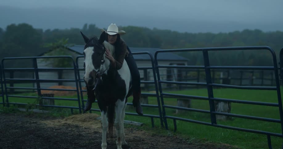Cowgirl on top of her horse in a pasture embracing it