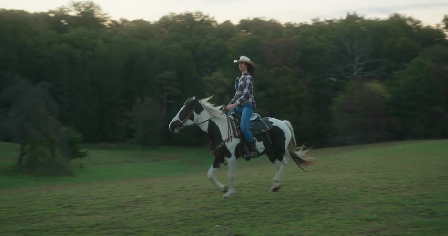 A woman is riding a horse on the ranch