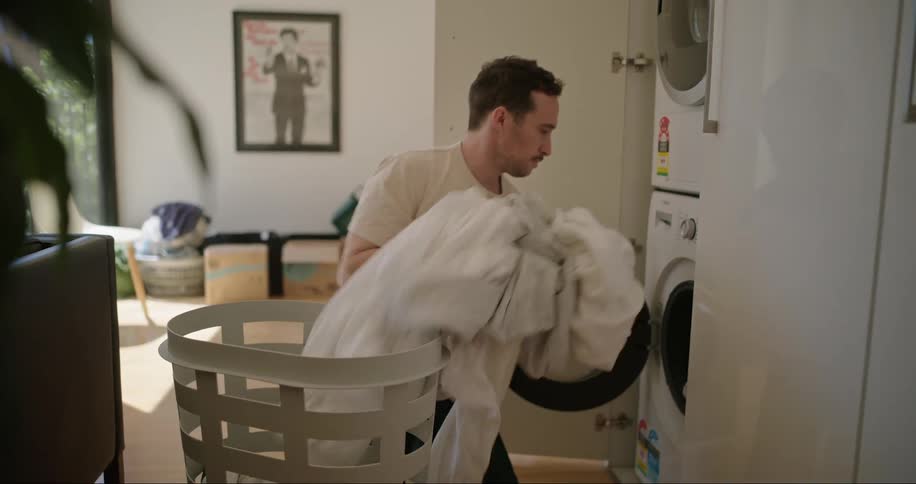 A man loads a washing machine with laundry