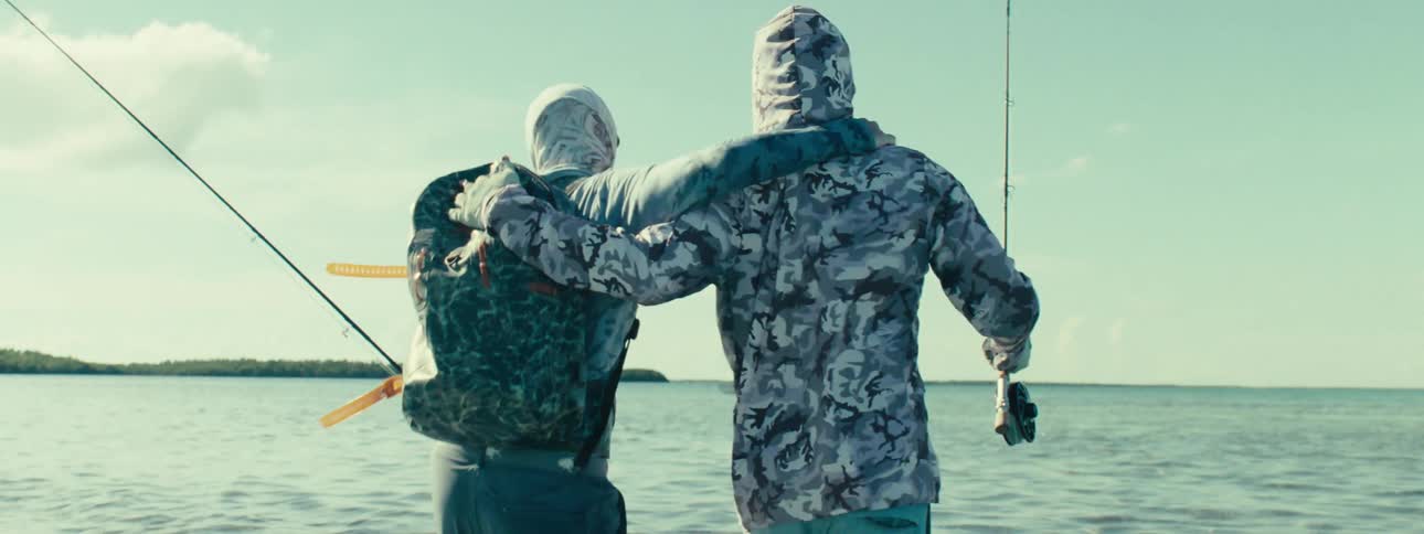Friends hugging each other while fishing in the sea