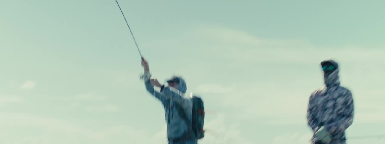 Two people are fishing in shallow water
