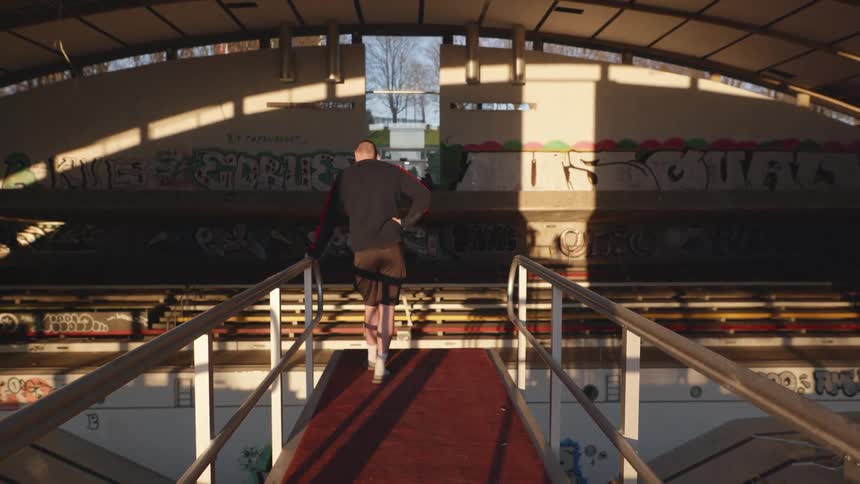 Man standing on a diving platform looking at an abandoned olympic pool