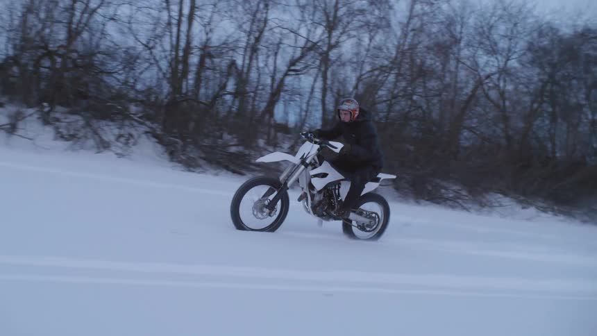 A man riding a motorcycle in the snow during the day