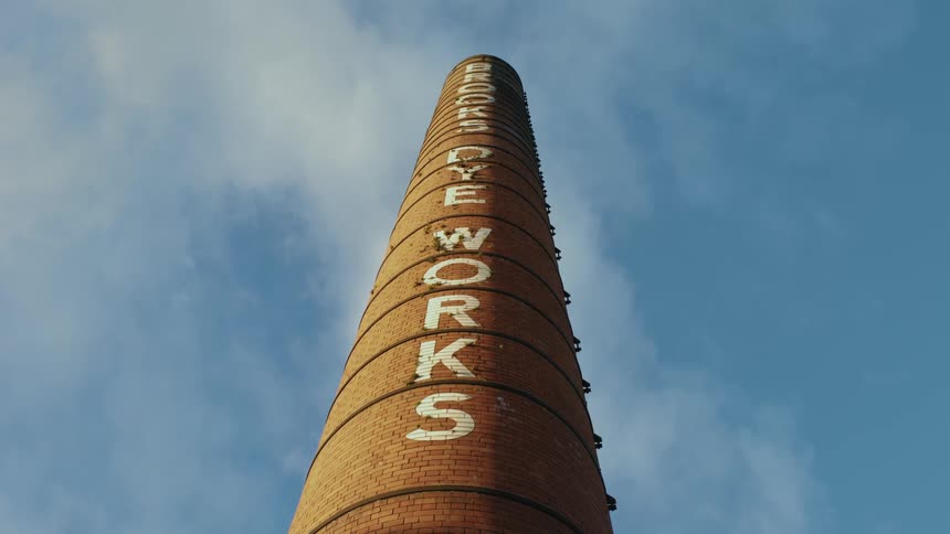 Straight upward perspective of a round industrial smoke stack column against a blue sky