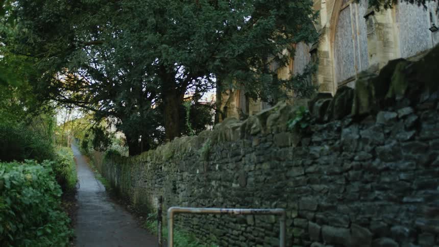 A path next to a wall of boulders and some vegetation around it
