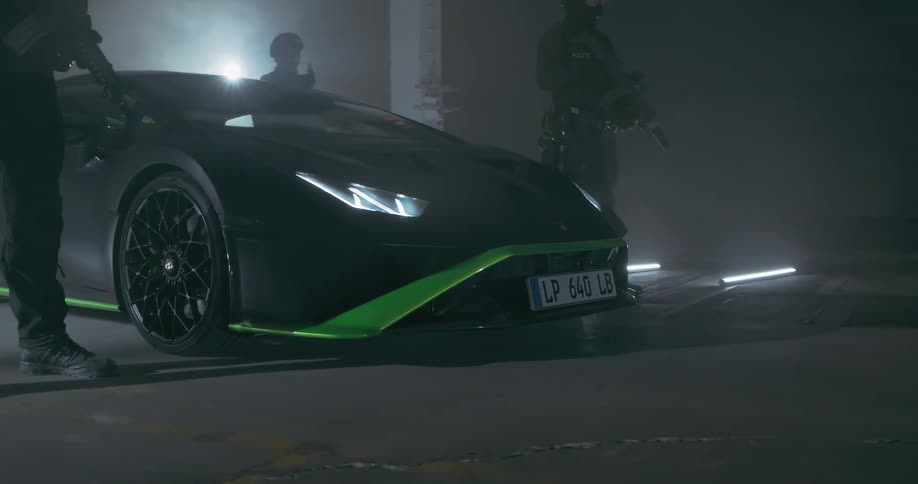 Three armed men stands near a lamborghini in a garage at night