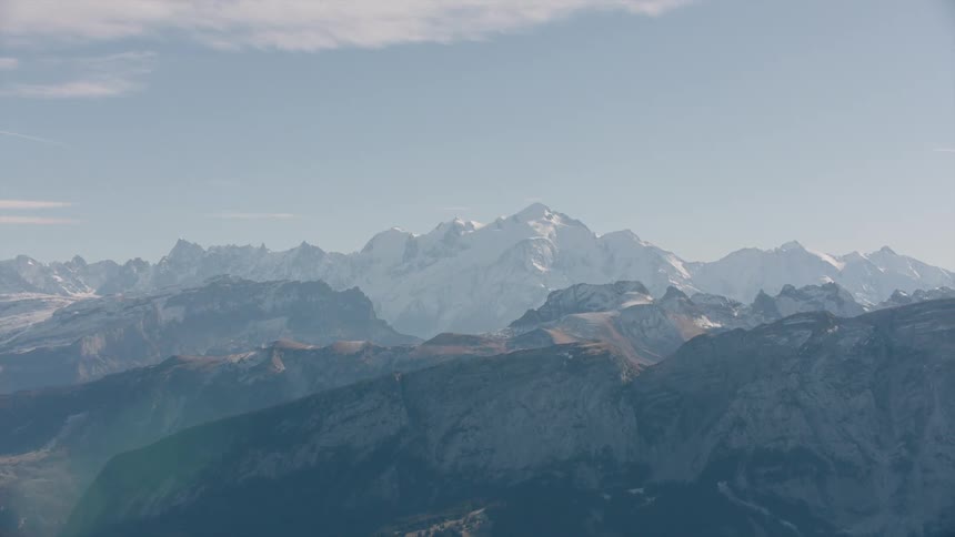 Snowcapped mountains behind a forested mountain range