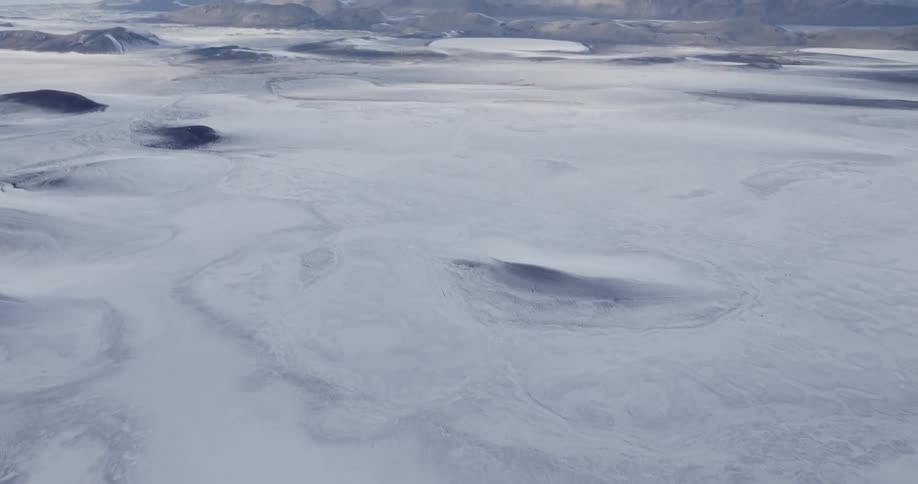 An aerial view of a frozen landscape with mountains in the distance