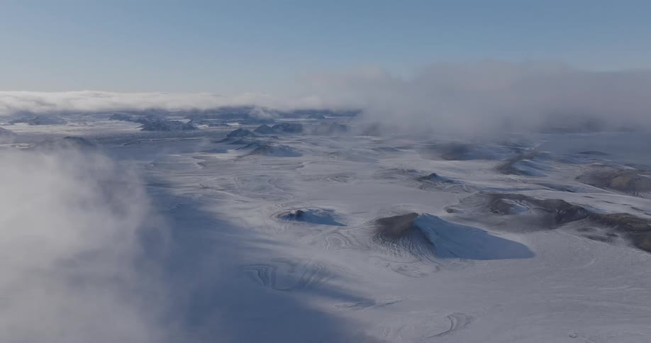 Aerial view of clouds rolling over a snowy landscape