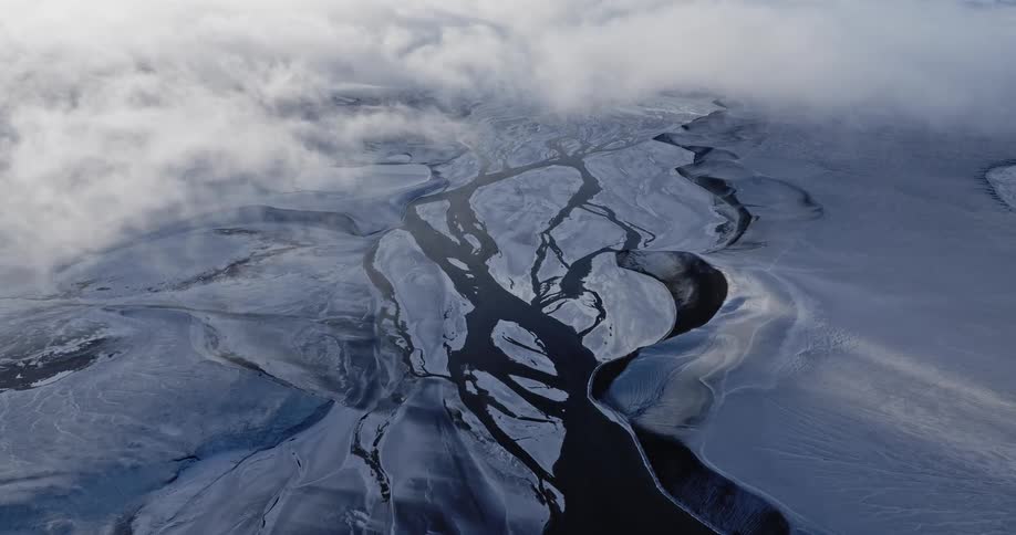 Clouds flow over river passing through ice covered terrain