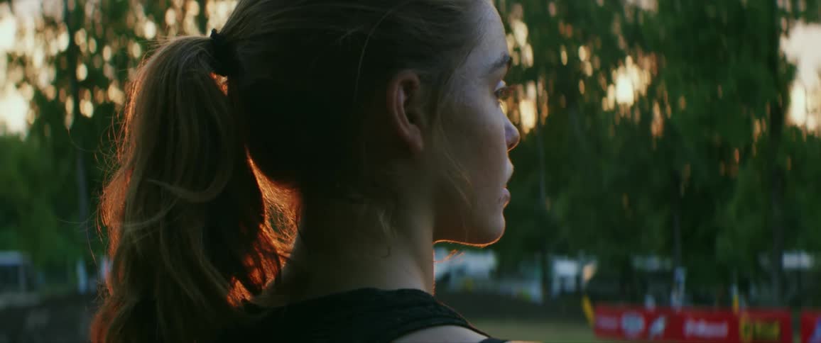A teen standing outdoor at sunset with eyes fixed towards something