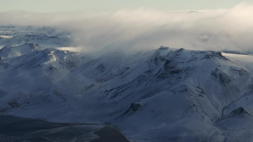 A cloud hangs over snowcovered mountains