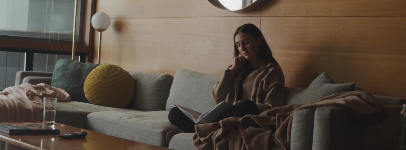 A woman cries while sitting reading a book