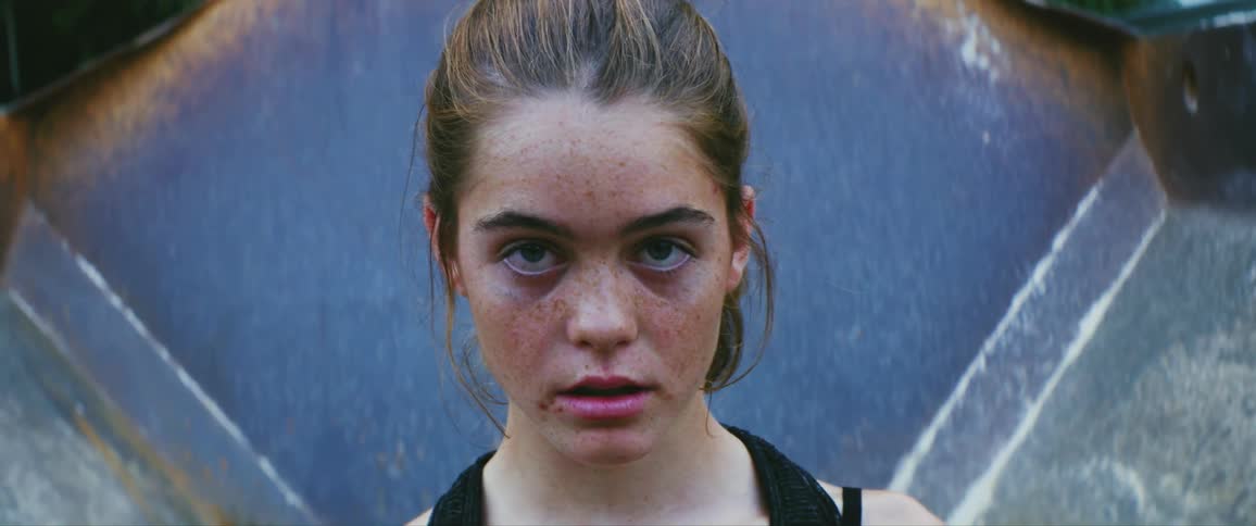 Girl with many freckles on her face and wearing a black tank top breathes heavily