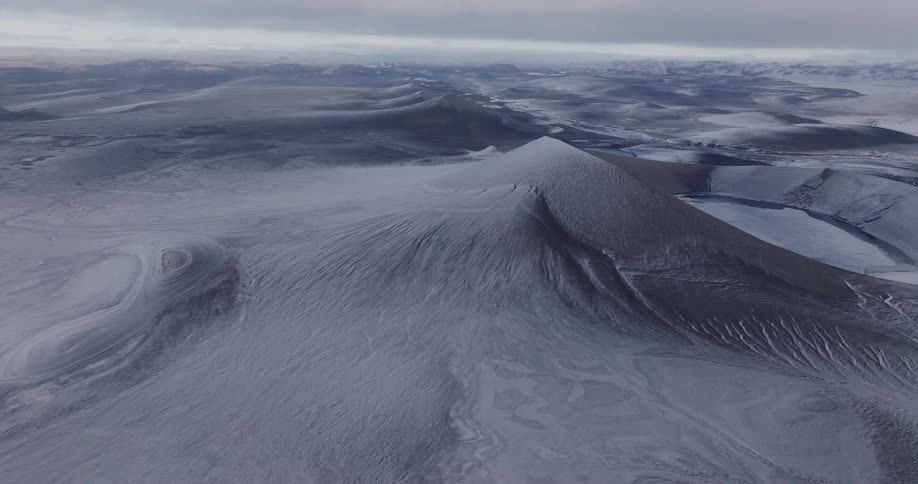 Aerial landscape of grayish mountains and plateaus under a cloudy sky